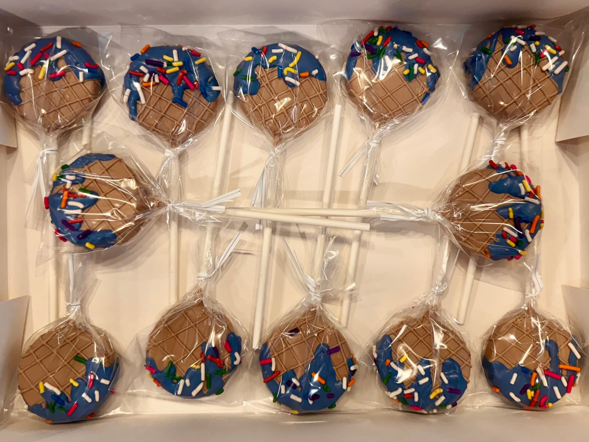 Golf-themed cake pops spelling GOLF, with a golf ball, clubs, sunglasses and the number 30, on a stand.