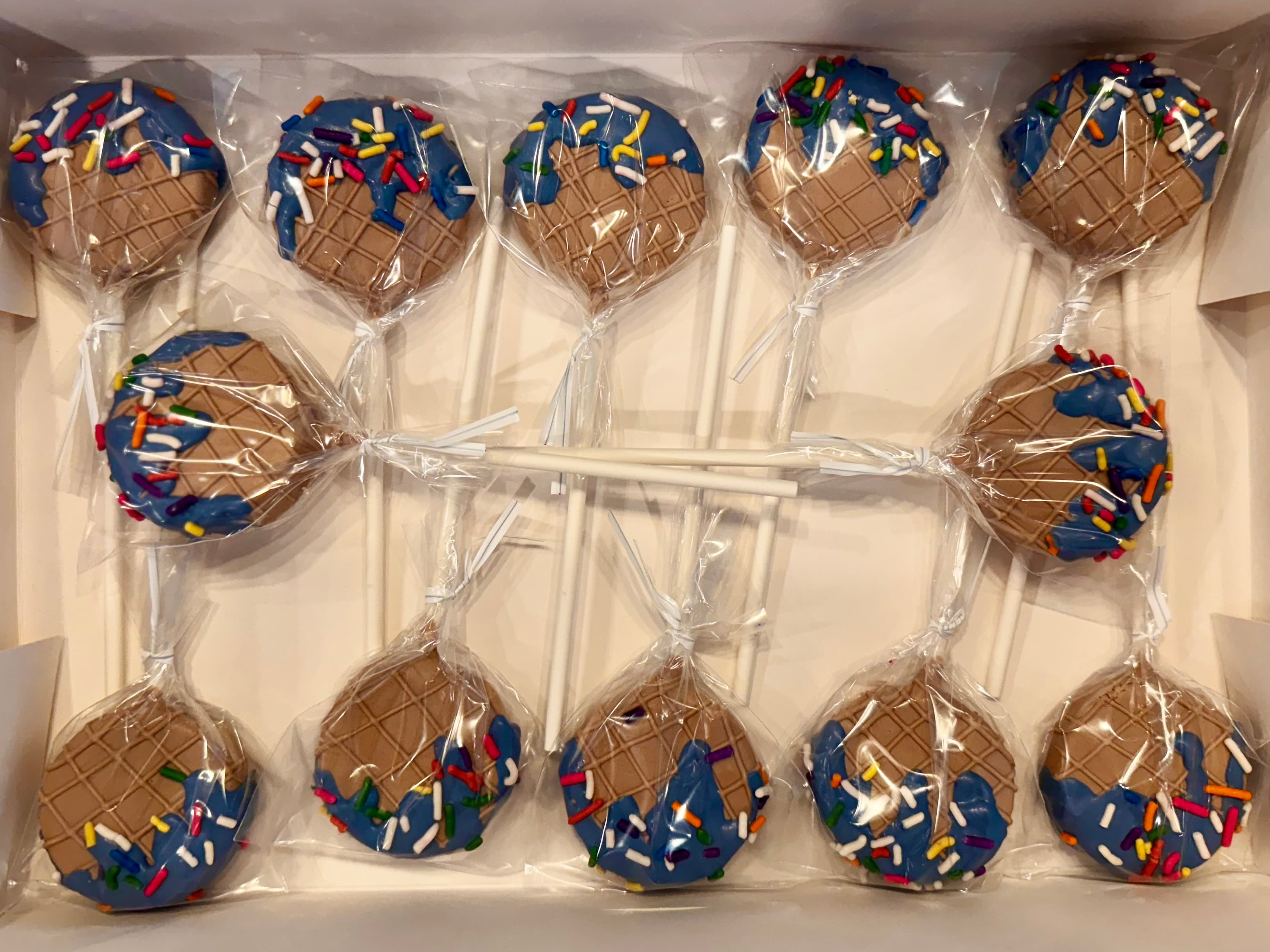 Blue cake pops with a waffle-cone pattern and rainbow sprinkles, individually wrapped in a box.
