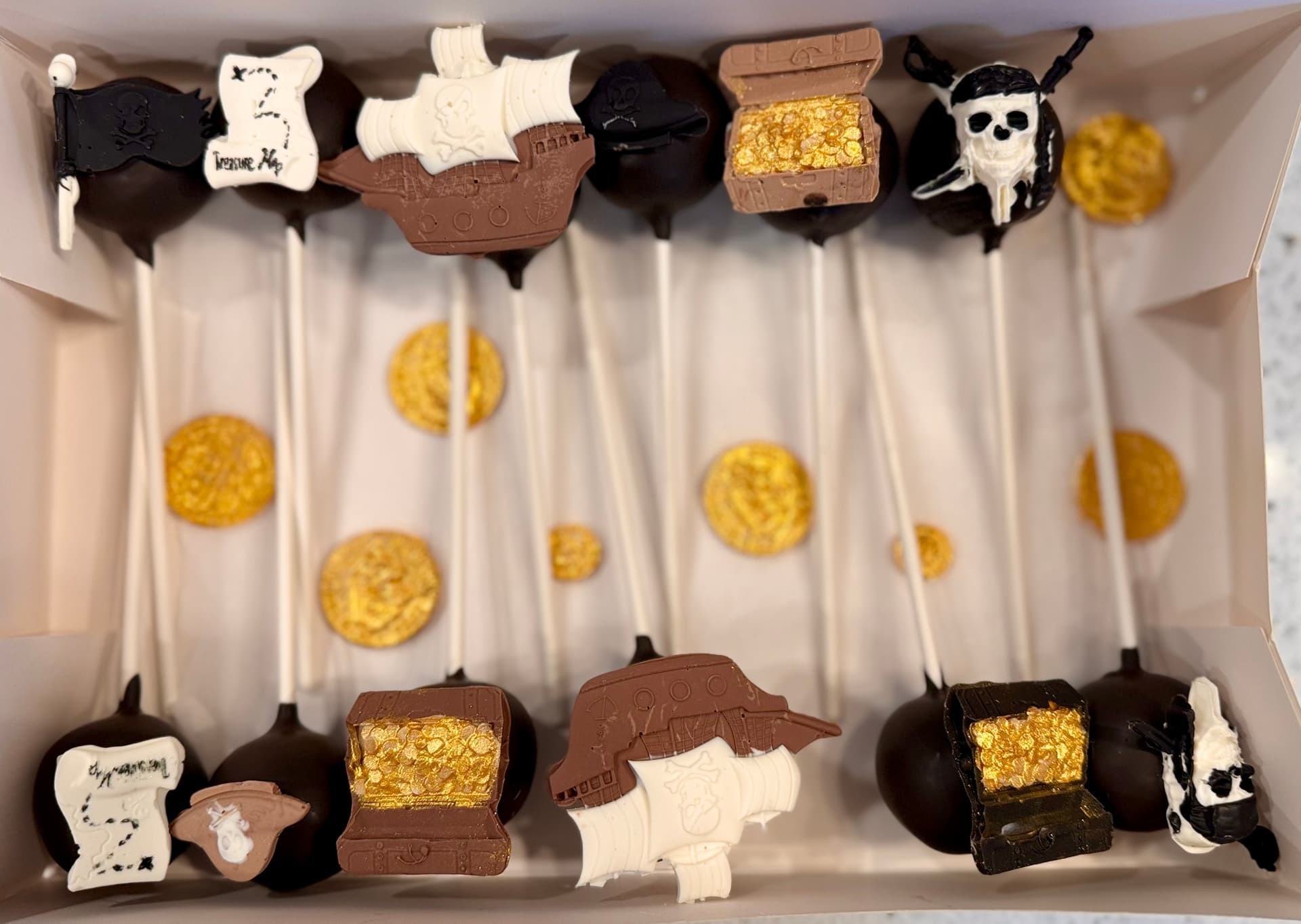 Pink and cream cake pops decorated with a cowboy hat, boot and cactus.
