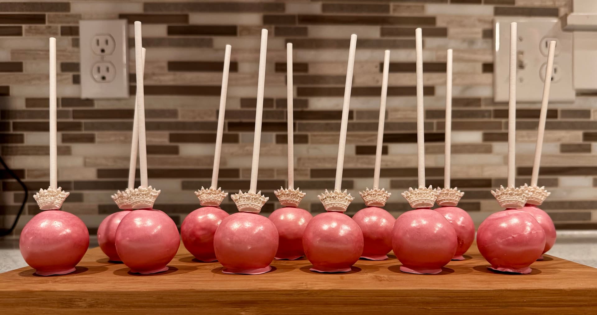 Black cat face cake pops with pale green eyes and pink noses, on a stand.