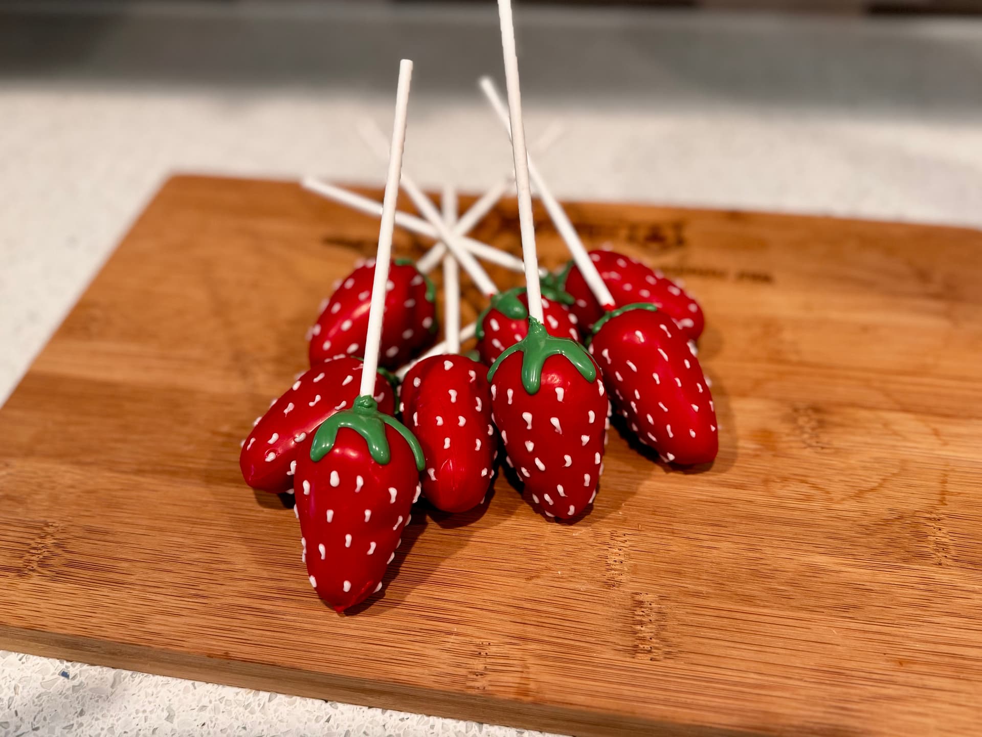 Strawberry-shaped red chocolate cake pops with white chocolate seed detailing.