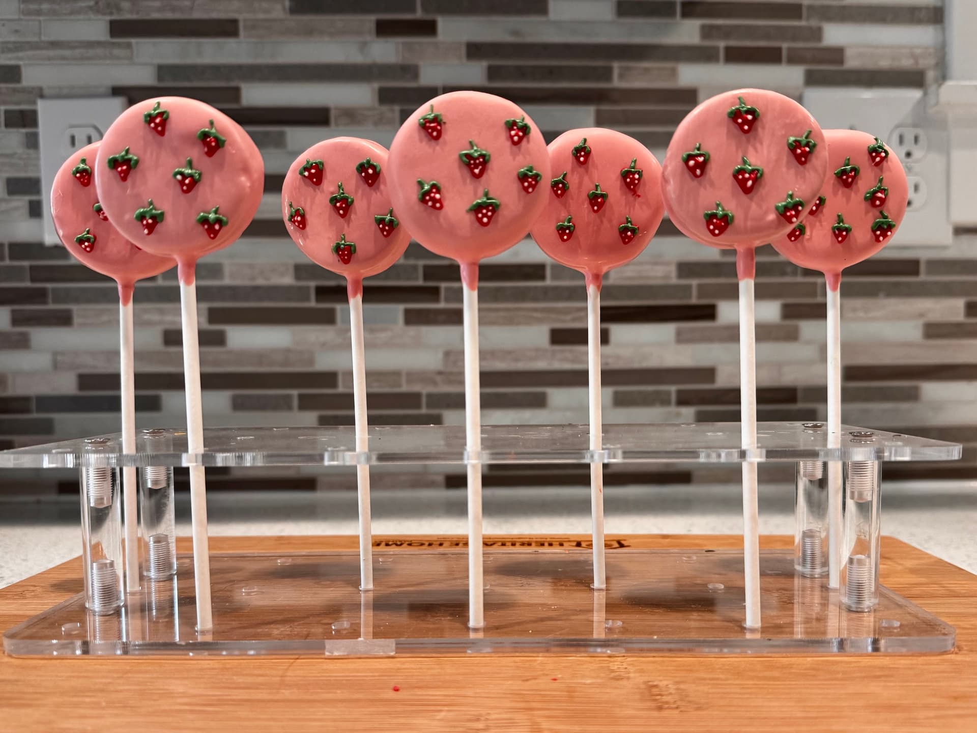 Pink cake pops covered in small fondant strawberry decorations.
