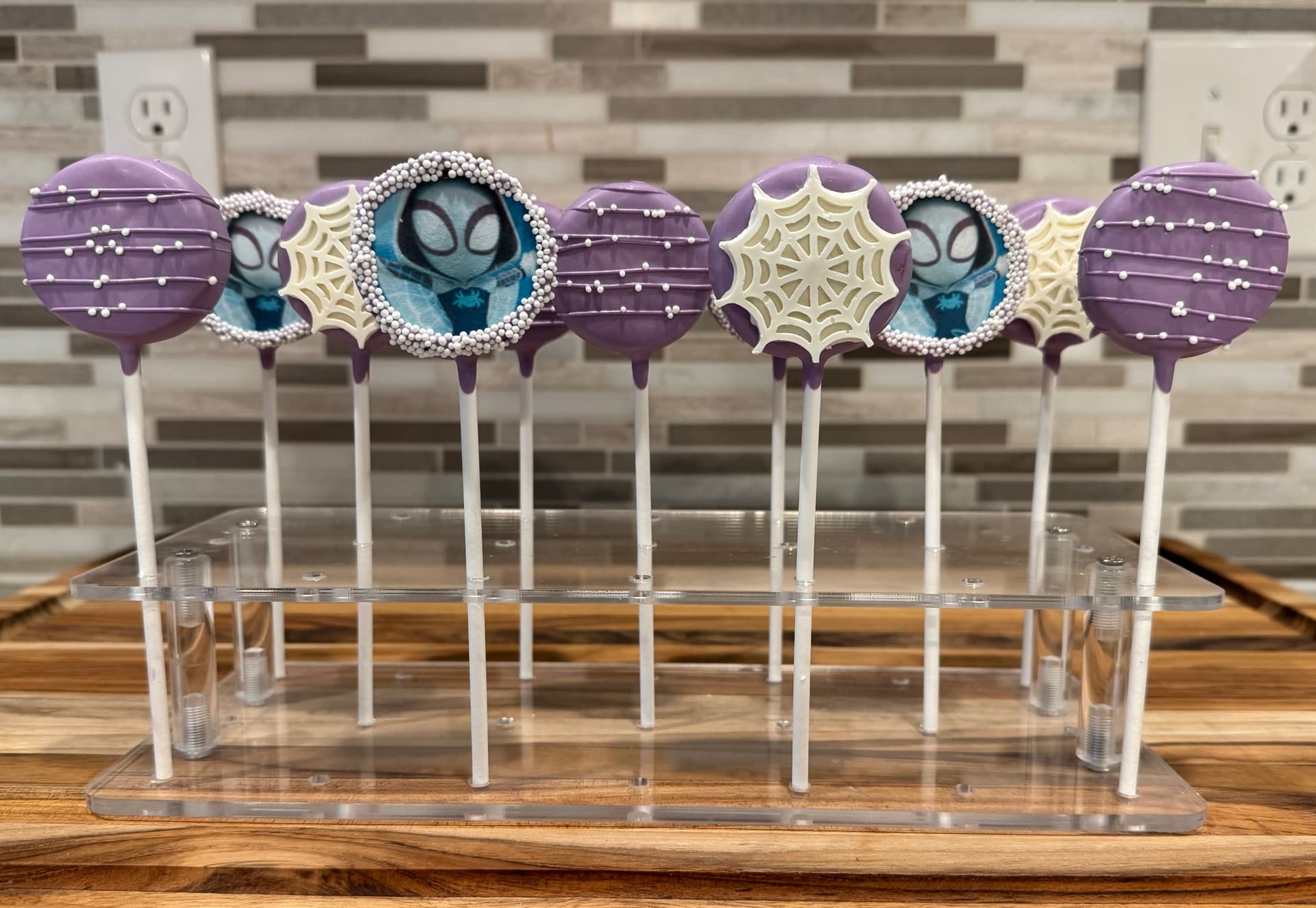 Cake pops decorated with a purple Spider-Man design.