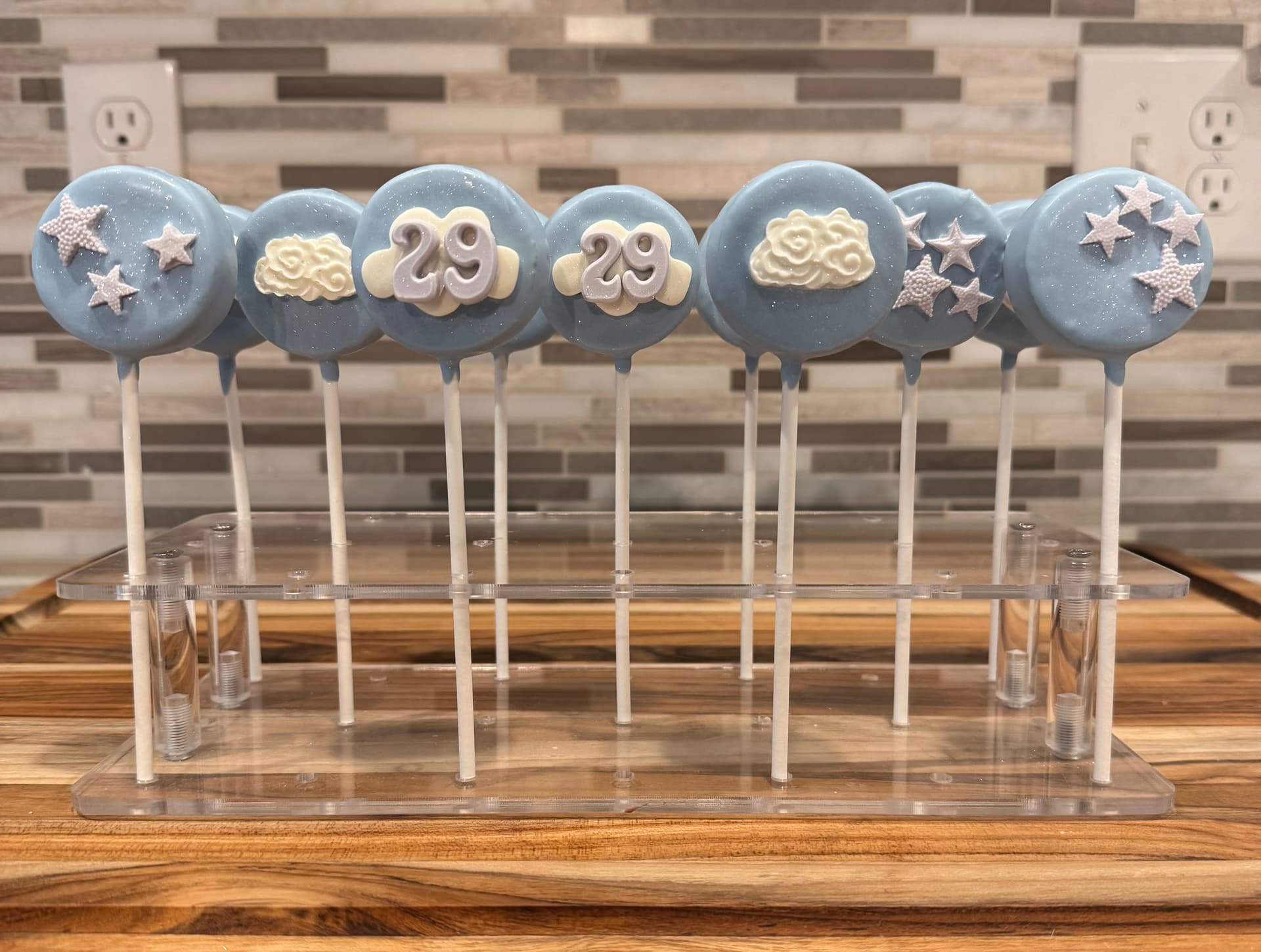 Cake pops with a cloud design and the number 29 for a birthday.