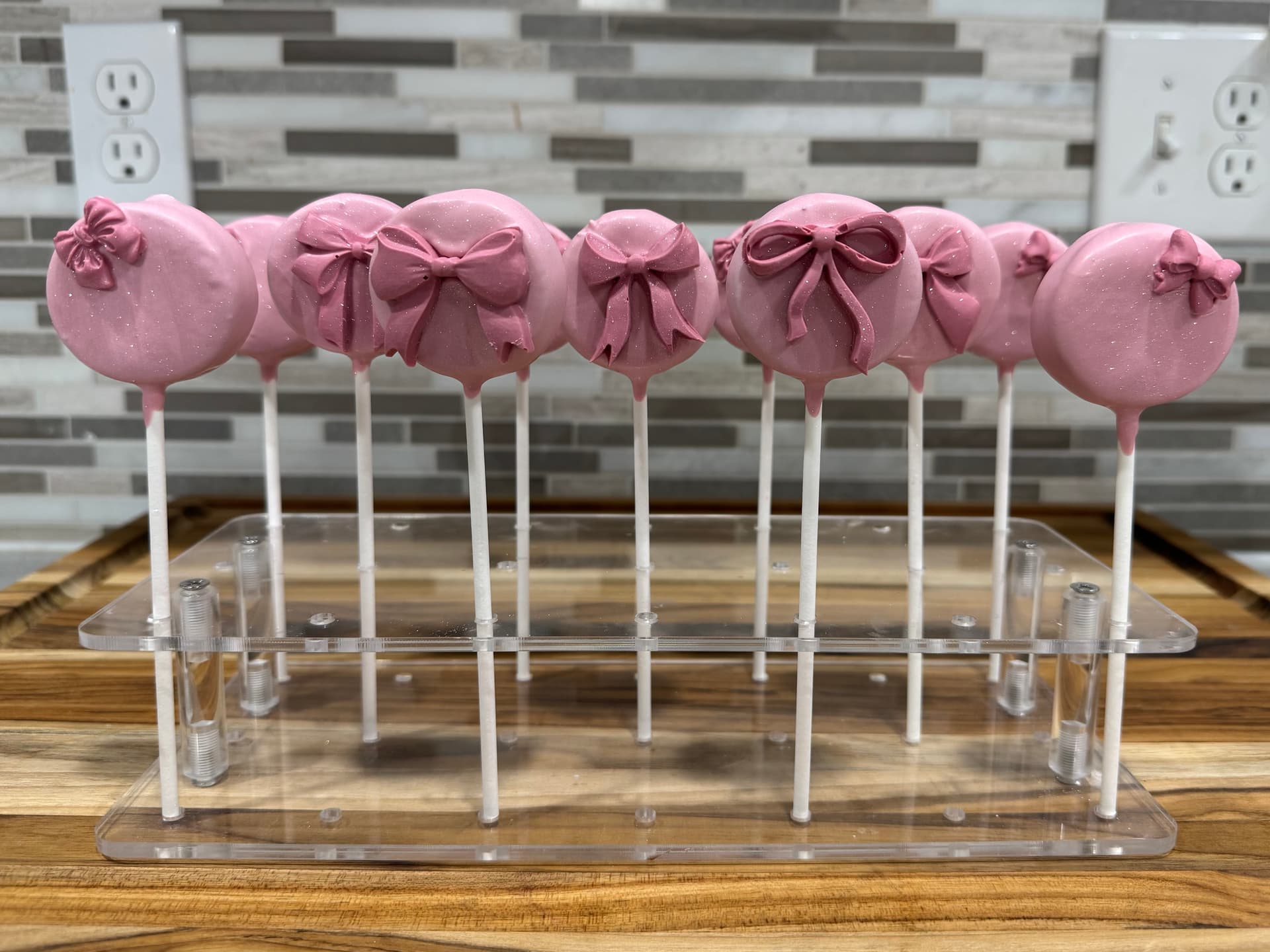 Cake pops decorated with a pink bow design.