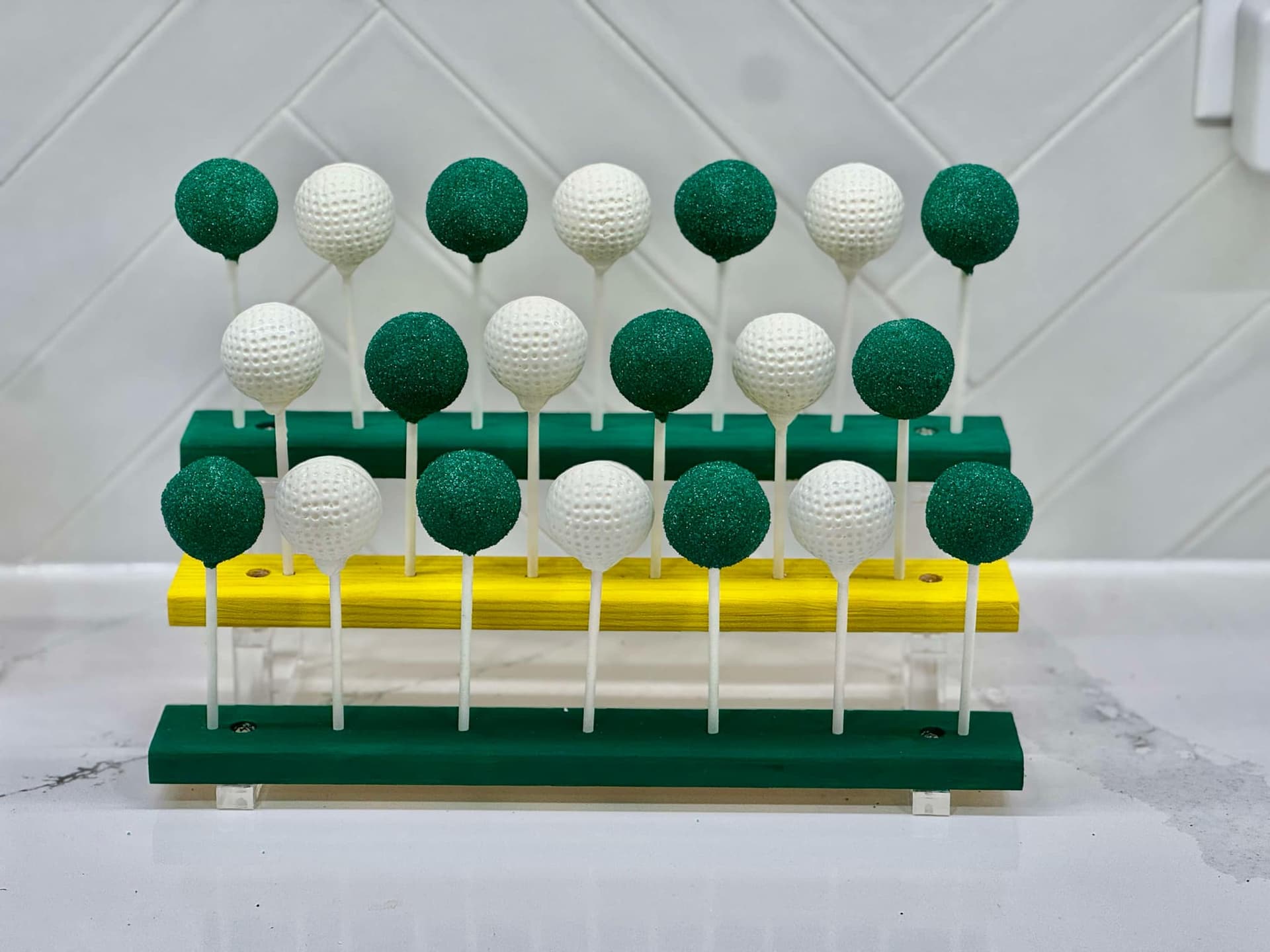 A cake decorated with fondant golf balls on green buttercream grass.